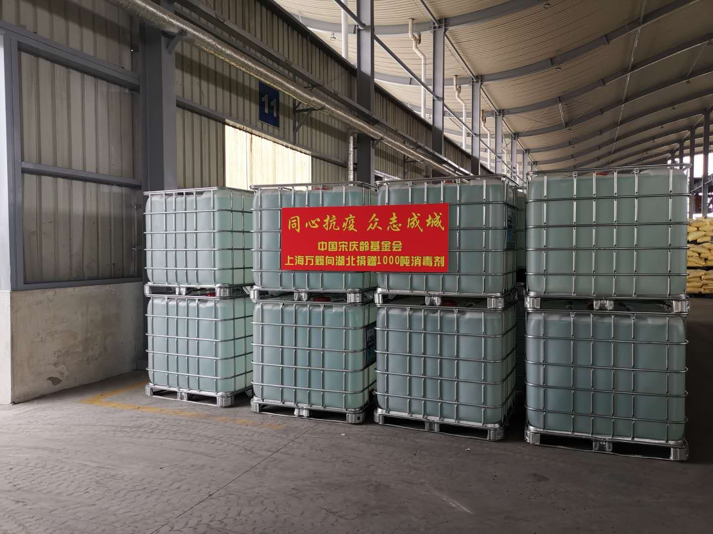 货车车厢内整齐码放的IBC吨桶,前方悬挂同心抗疫众志成城红色横幅