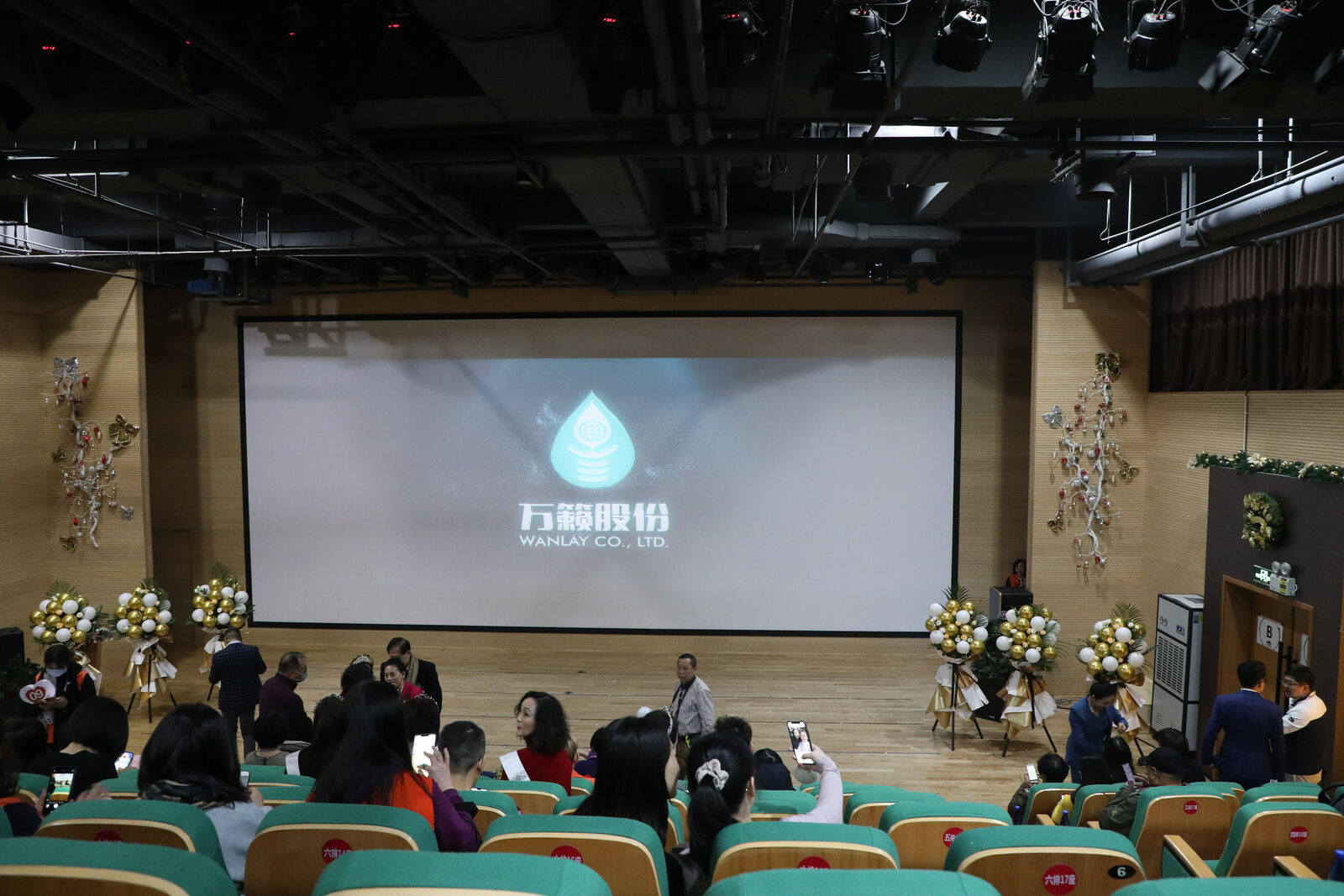 为爱点灯慈善义卖活动现场,大屏幕显示万籁股份标识