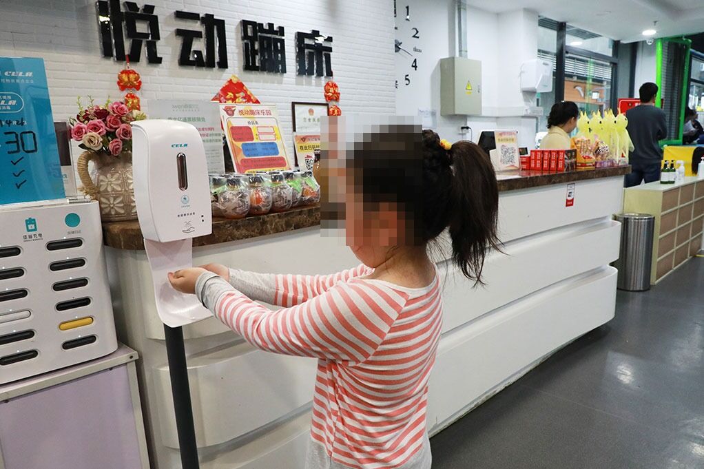 入场儿童在悦动蹦床乐园前台旁使用感应式免洗手消毒机（人脸已做模糊处理）